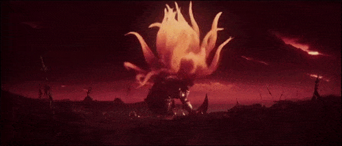 a man is standing in front of a large explosion in the middle of a field .