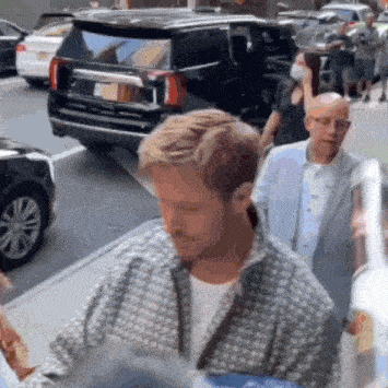 a group of people are walking down a street with a suv in the background