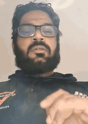 a man with glasses and a beard is wearing a black shirt that says evid on it