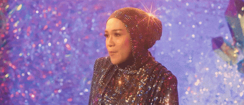 a woman in a hijab is standing in front of a purple background with glitter