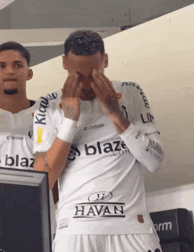a man in a blaze shirt wipes his face