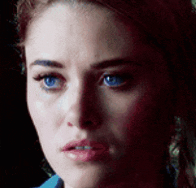 a close up of a woman 's face with blue eyes and a blue shirt .
