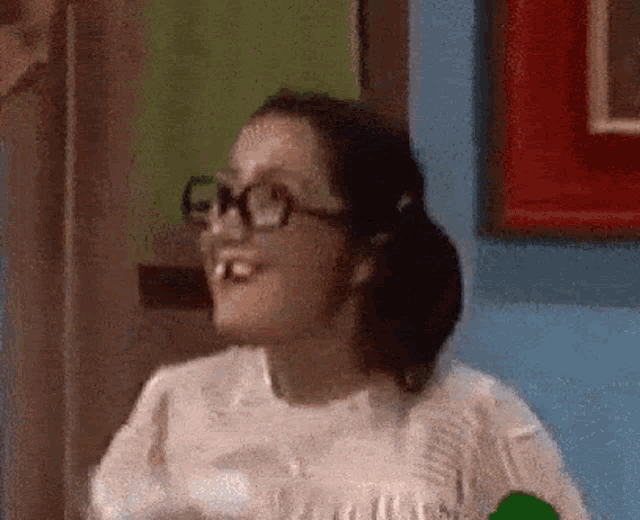 a woman wearing glasses is making a funny face while holding a bottle of water .