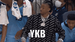 a man wearing a sweater that says ykb is standing in a crowd