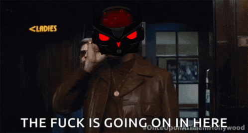 a man in a leather jacket is standing in front of a door with the words " the fuck is going on in here " on the bottom