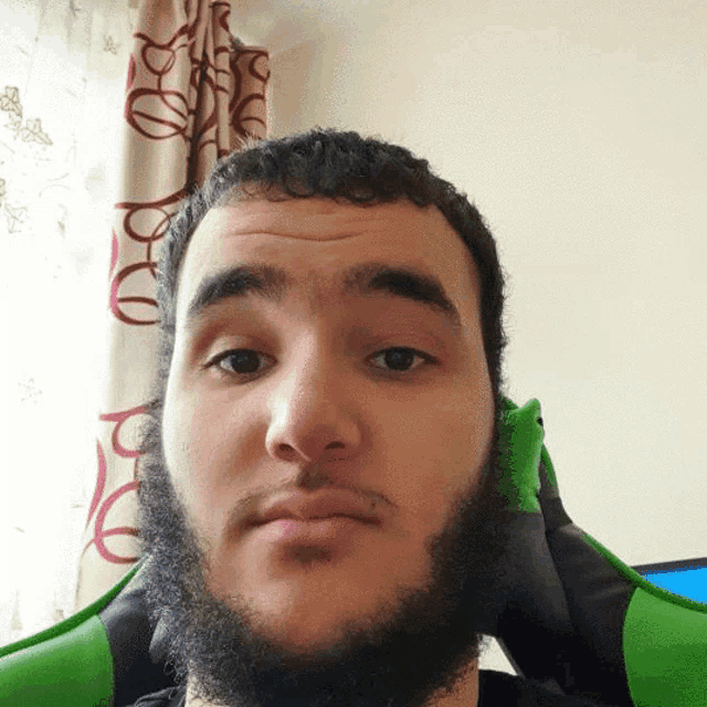 a man with a beard is wearing a green shirt