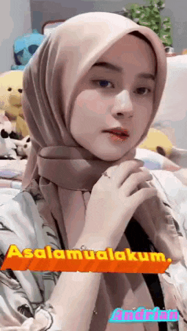 a woman wearing a hijab is standing in a room with stuffed animals in the background .