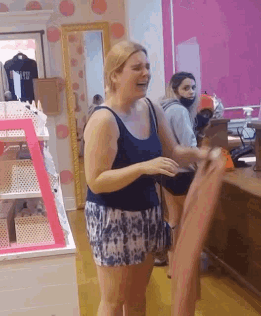 a woman in a blue tank top is standing in a store