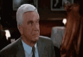 a man in a suit and tie is looking at a woman in a red dress .