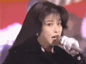 a woman is singing into a microphone while wearing ear muffs .