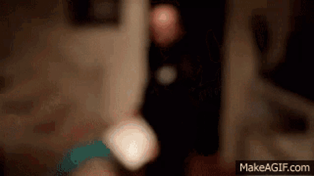a blurry picture of a person standing in a dark room with a candle .