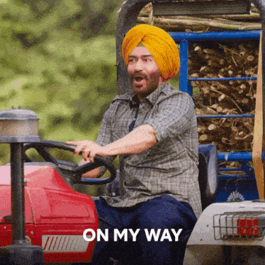 a man in a turban is driving a tractor with the words " on my way " behind him