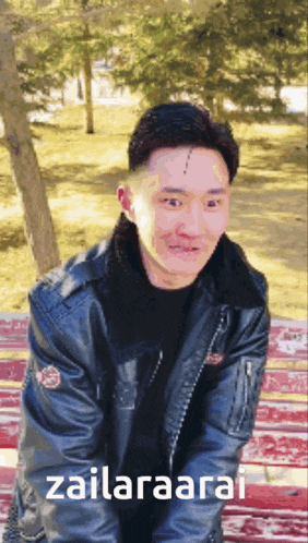 a man in a black leather jacket is sitting on a red bench with the words zailanaarai written on the bottom
