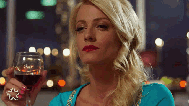a woman in a blue dress is holding a glass of wine with a star on her finger