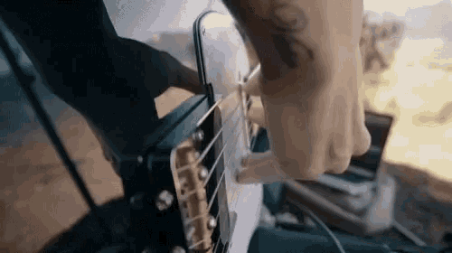 a man with a tattoo on his arm is playing a guitar