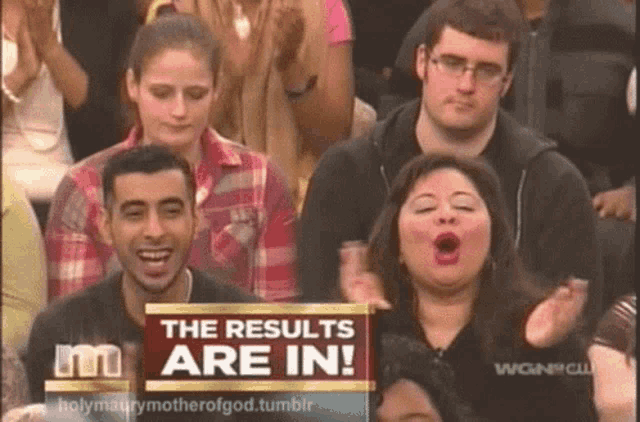 a group of people sitting in front of a sign which says the results are in