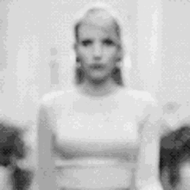 a black and white photo of a woman in a white dress standing in front of a wall .