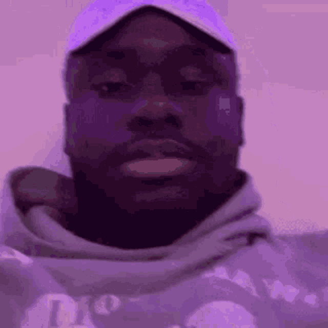 a close up of a man wearing a hat and a purple hoodie .