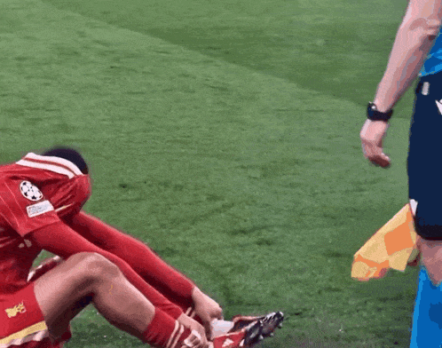 a soccer player is sitting on the grass with his head in his hands