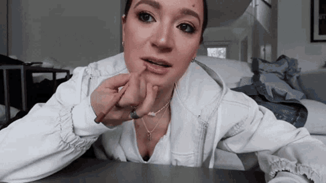 a woman in a white jacket is applying lip gloss to her lips .