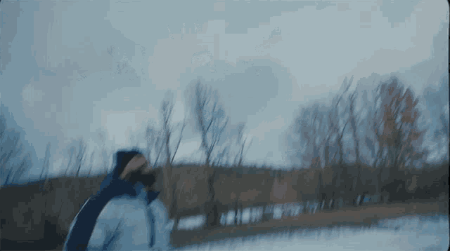 a blurry picture of a person walking in the snow with trees in the background