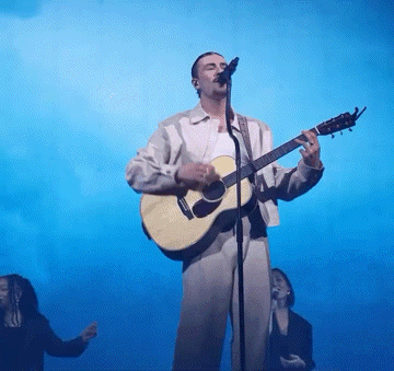 a man is singing into a microphone while holding a guitar