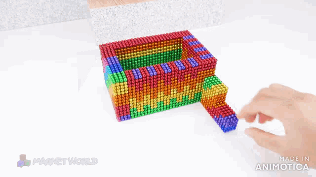 a person is playing with a rainbow colored toy that is made by magnetworld