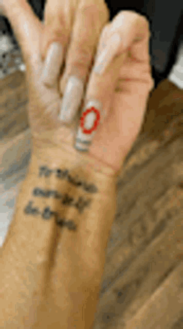 a close up of a person 's wrist with a tattoo on it and a ring on it