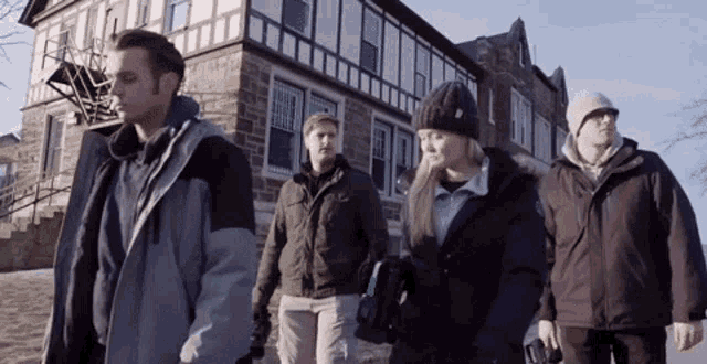 a group of people are walking in front of a brick building