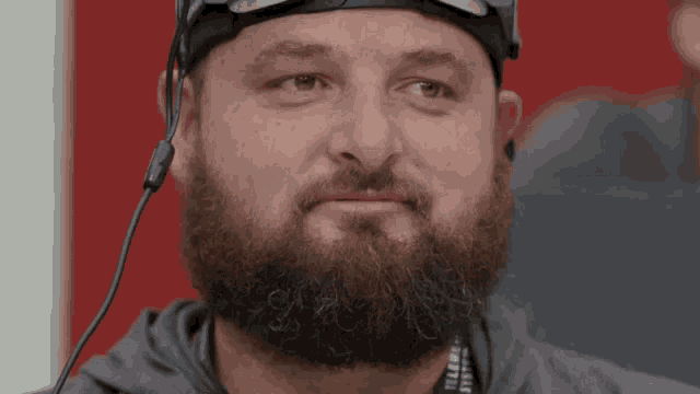 a man with a beard wearing a headset and sunglasses .