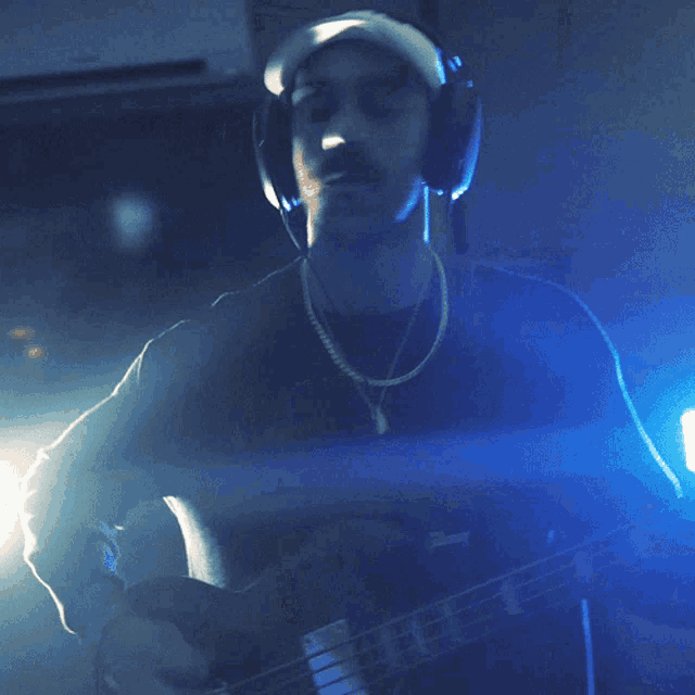 a man wearing headphones plays a guitar in a dark room