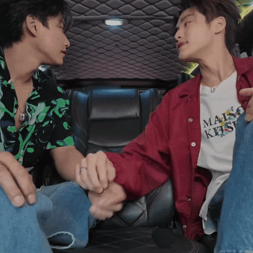 a man wearing a maison kitsune t-shirt holds hands with another man