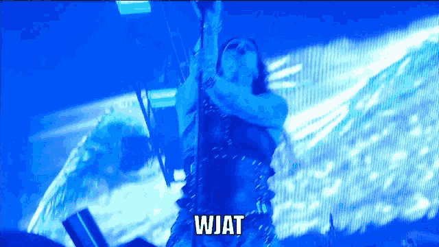 a woman in a blue dress is dancing in front of a blue background and the word wjat is above her