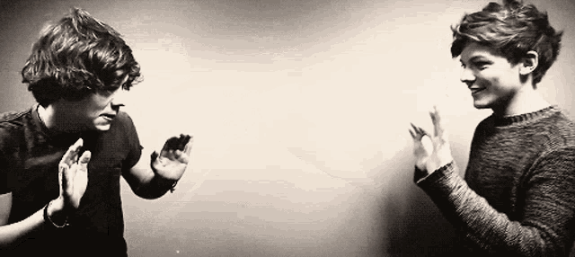 a black and white photo of two young men clapping