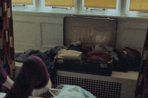 a suitcase filled with clothes sits on a radiator in front of a window