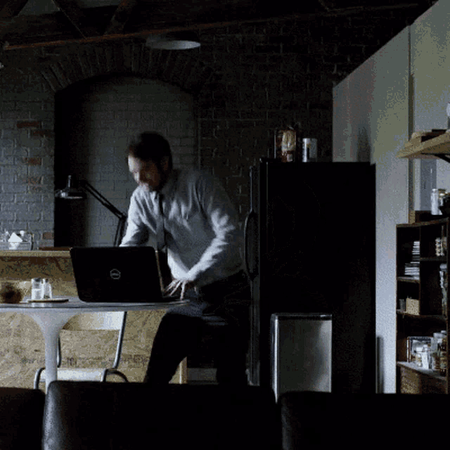 a man jumps in front of a laptop in a kitchen