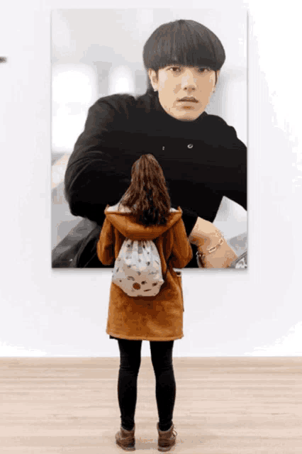 a woman is looking at a painting of a man