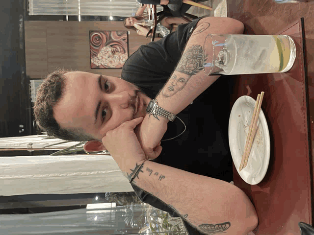 a man with a tattoo on his arm that says all is love sits at a table