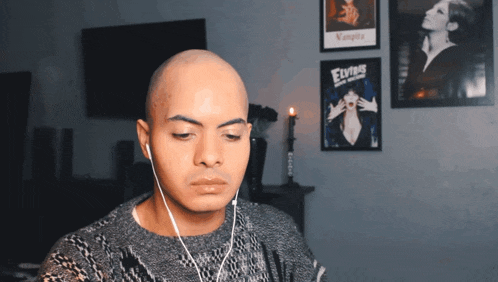 a man wearing ear buds looks at a vampire poster