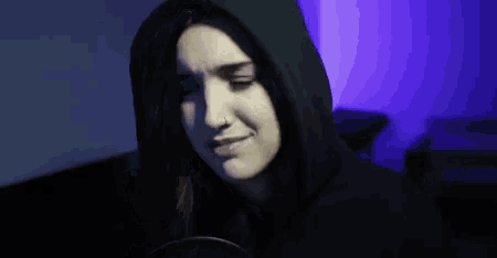 a woman in a hooded sweatshirt is sitting in front of a microphone .