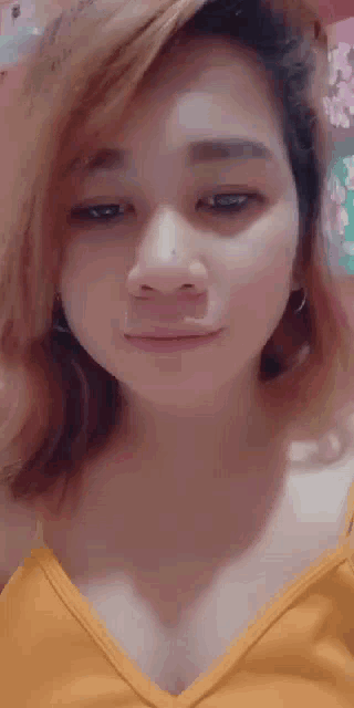 a woman in a yellow shirt is making a funny face .