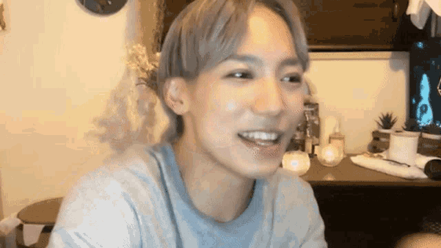 a young man with short hair is smiling and looking at the camera while sitting at a table .