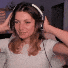 a woman is wearing headphones and smiling while sitting in front of a computer screen .