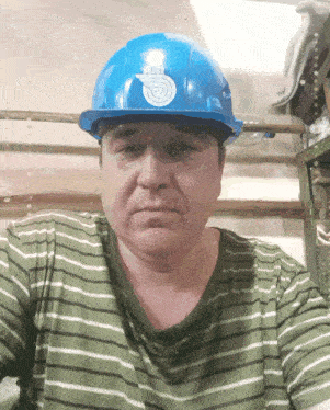 a man wearing a striped shirt and a blue hard hat with a spiral on it