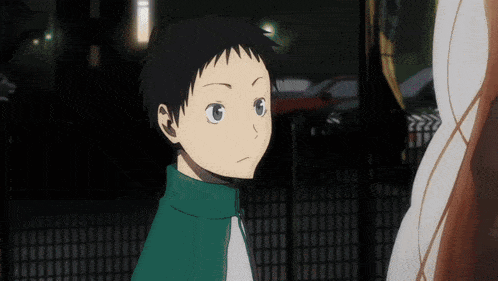 a young boy with black hair and blue eyes is standing in front of a fence
