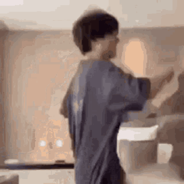 a man in a blue shirt is standing in a room with his hands outstretched .