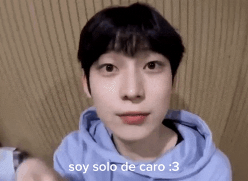 a close up of a person wearing a blue hoodie with the words `` soy solo de caro '' on it .