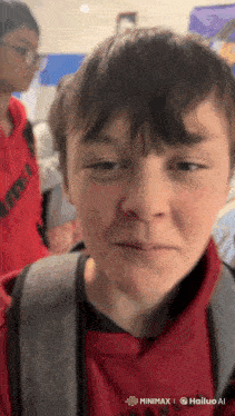 a young boy wearing a red sweatshirt and a backpack looks sad