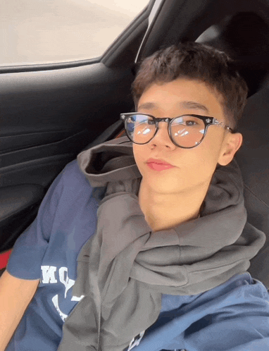 a young man wearing glasses and a blue shirt that says kc