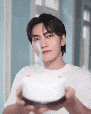 a young man is holding a birthday cake with a blue candle in his mouth .